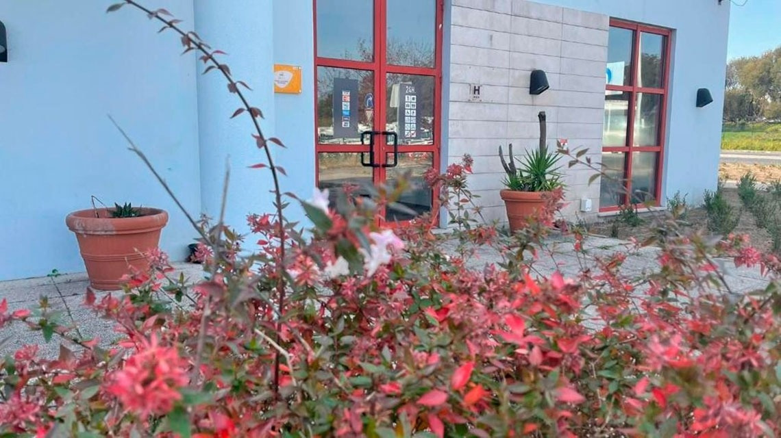Fachada do Flag Hotel Porto-Maia com plantas floridas em destaque