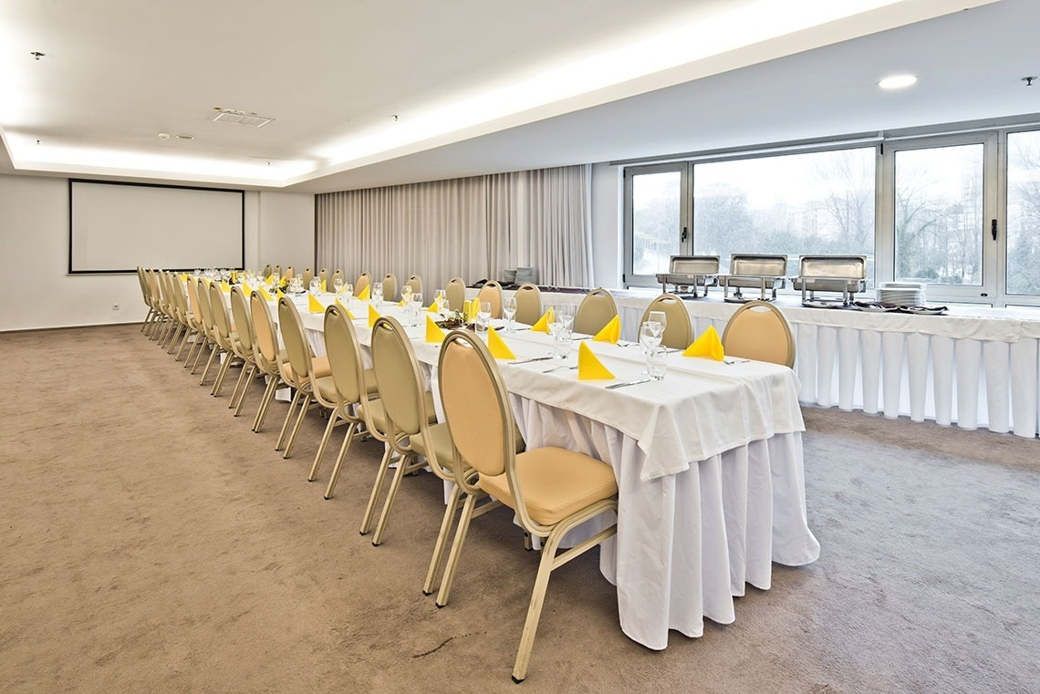Banquet room at Golden Tulip Sao Joao da Madeira, set with tables, chairs, and projection screen.