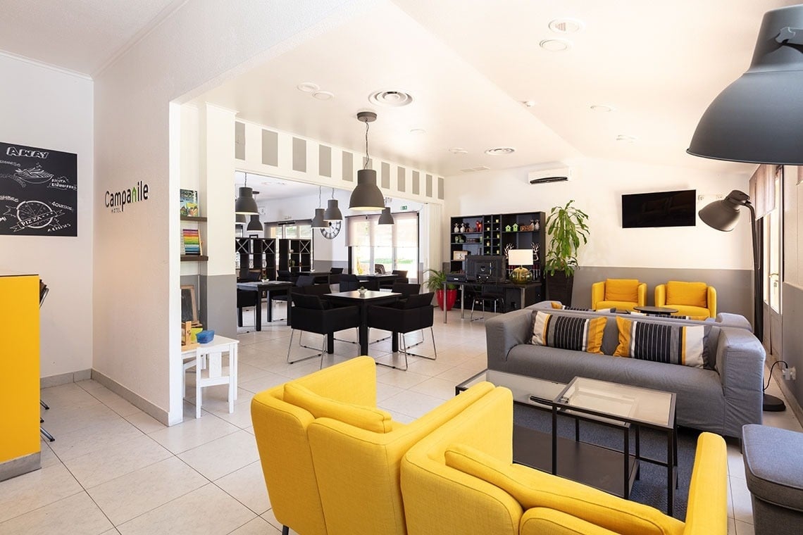 Lounge moderno do Campanile Setúbal com sofás amarelos vibrantes e área de refeições elegante.