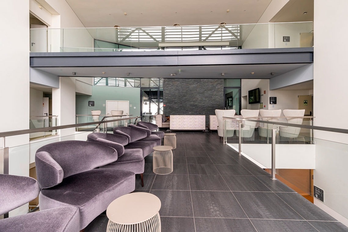Lounge moderno com sofás roxos e vista para o Monchique Resort & SPA by Flagworld Hotels.