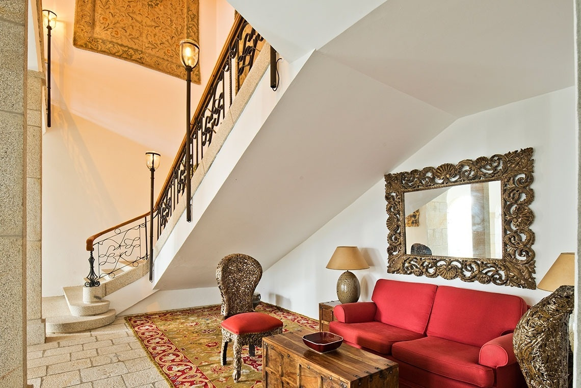 Sofá rojo y escalera elegante en Lam Hotel Convento do Desagravo | Web oficial.