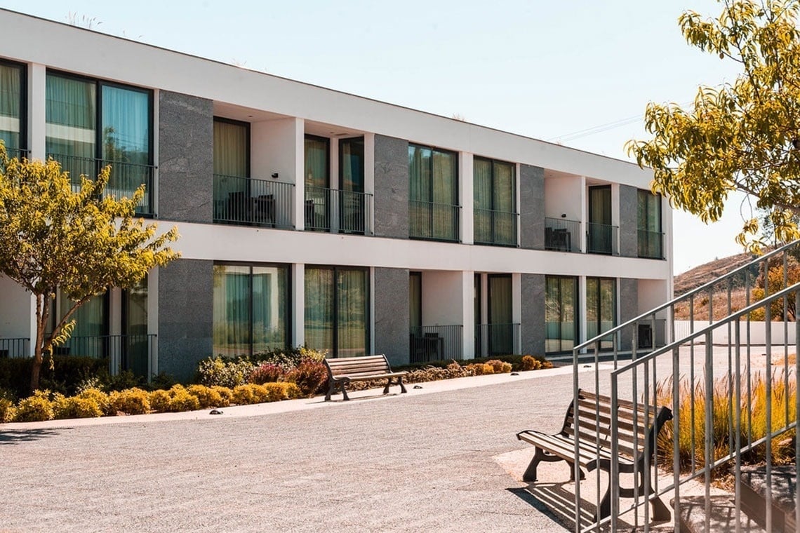 Monchique Resort & SPA: Fachada moderna com varandas, jardins e bancos ao ar livre.