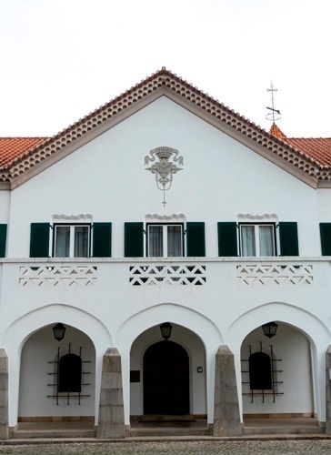 a white building with green shutters and a cross on the roof