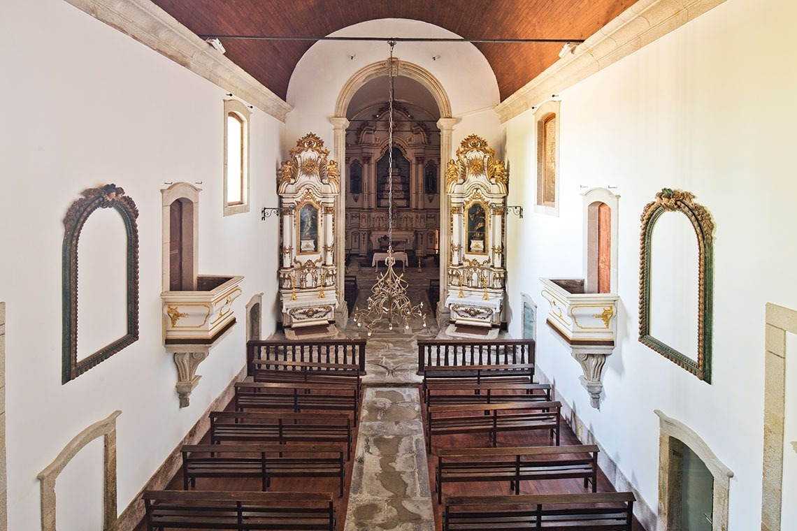 Interior de iglesia de Lam Hotel Convento do Desagravo: bancos de madera, altar barroco dorado.