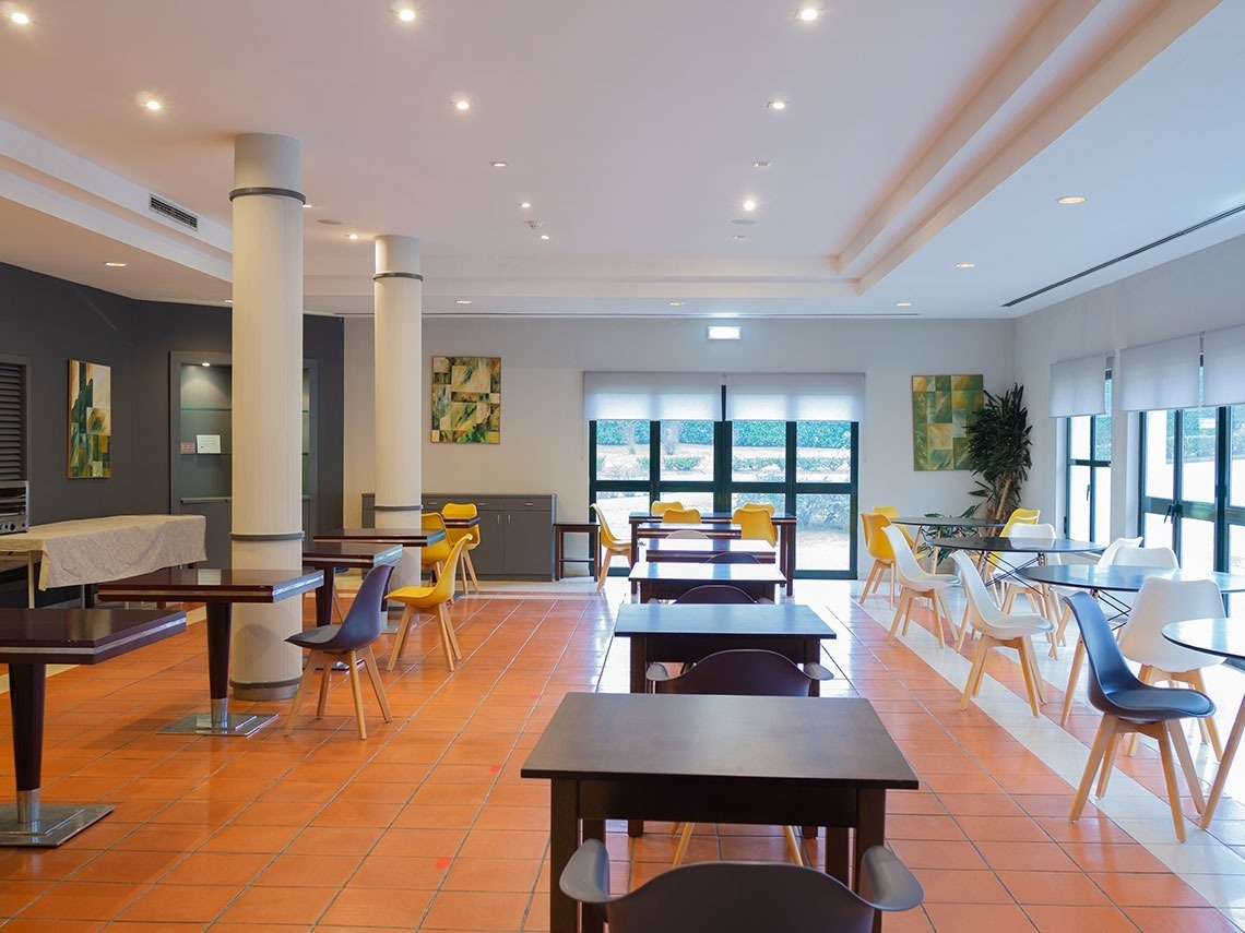 Salón luminoso con mesas y sillas, ideal para eventos en Flag Hotel Braga. ¡Reserva ya en el sitio web oficial!