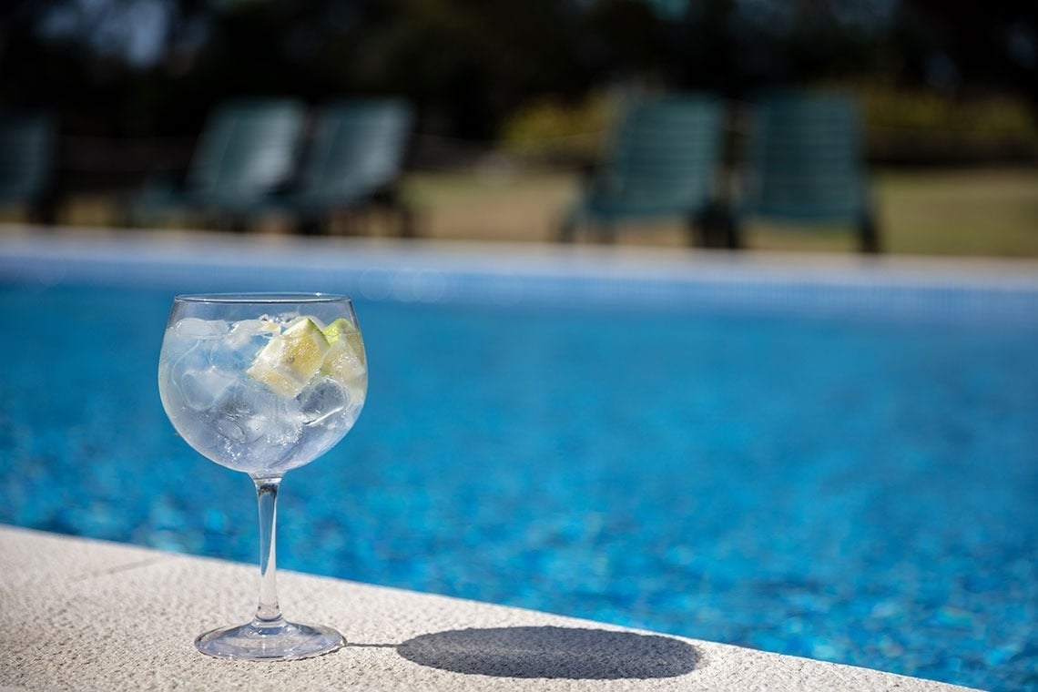 Gin tônica refrescante com limão à beira da piscina, perfeito para relaxar no Campanile Setúbal.