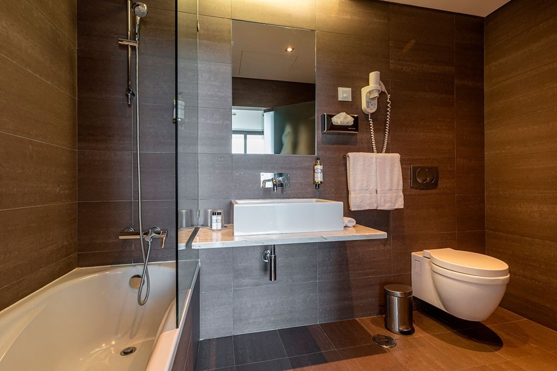 Banheiro moderno com banheira, pia e vaso sanitário em Monchique Resort & SPA by Flagworld Hotels | Website oficial.