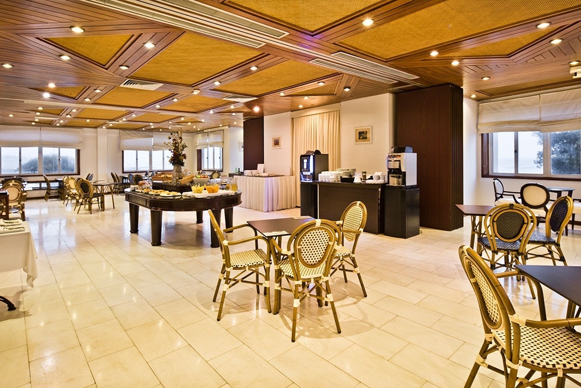 Elegant dining room at Lam Hotel Porto-Gaia, featuring rattan chairs & wooden tables. Official website.