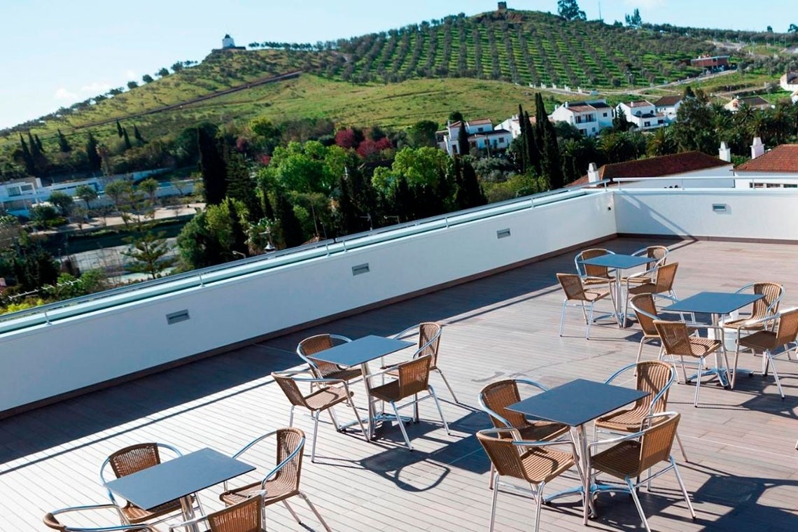 una terraza con mesas y sillas y un molino de viento en la distancia