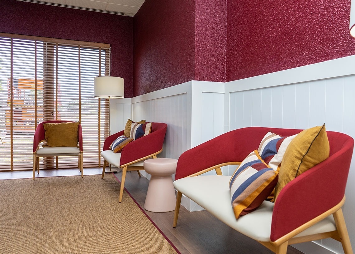 Modern lounge with red chairs and striped pillows at Flag Hotel Lisboa Oeiras.
