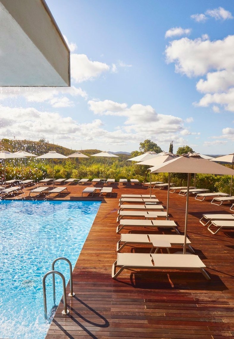 Piscina deslumbrante com espreguiçadeiras e guarda-sóis no Monchique Resort & SPA by Flagworld Hotels, website oficial.
