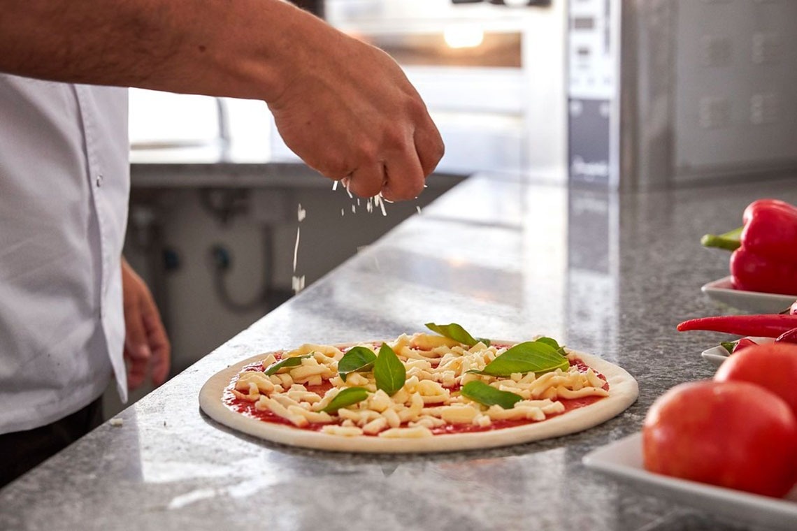Chef adiciona queijo a pizza no Monchique Resort & SPA by Flagworld Hotels | Website oficial
