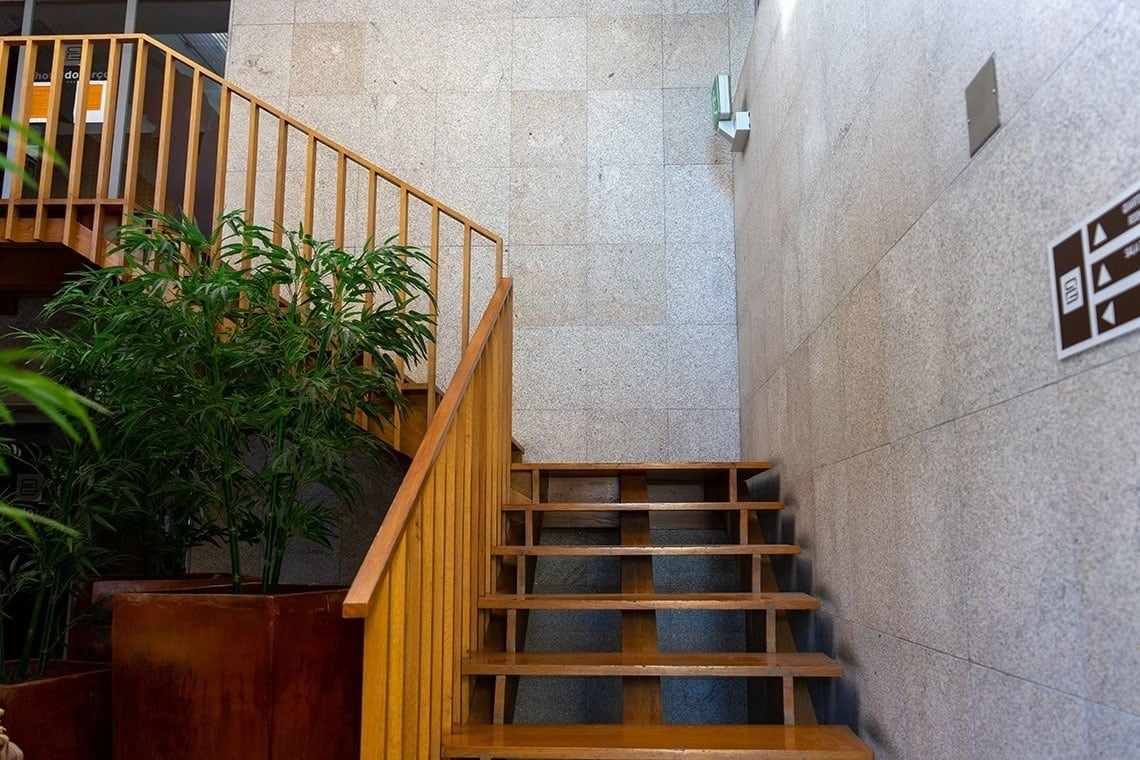 Modern wooden staircase at Flag Hotel Barcelos, an elegant hotel with lush plants.