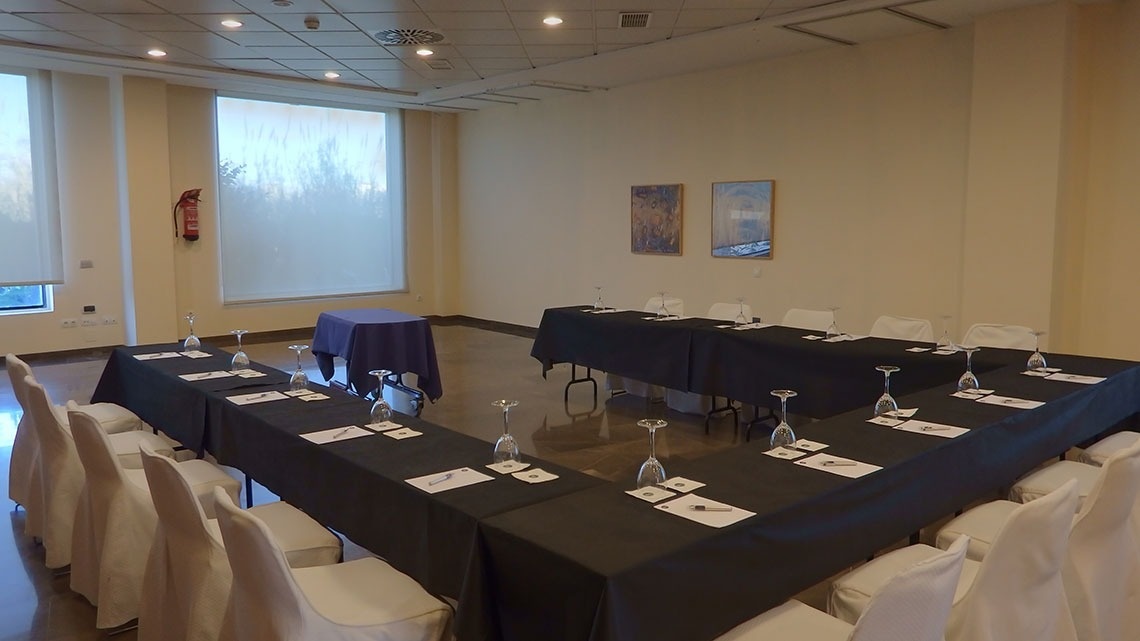 Salón de eventos del Flag Hotel Valencia con mesas dispuestas en U y sillas cubiertas.