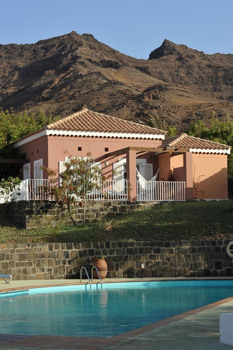 Piscina e casa colorida com montanhas ao fundo no Lam Hotel Foya Branca | Site oficial.
