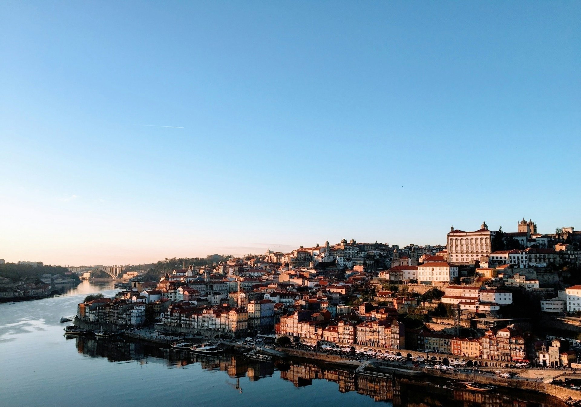 um castelo amarelo e vermelho em uma colina com a cidade ao fundo