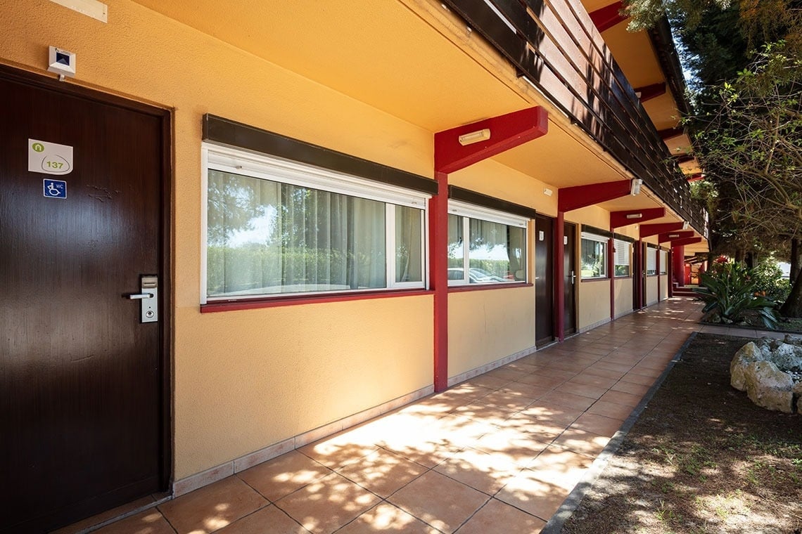Corredor externo com portas e janelas, sob a marquise do Campanile Setúbal | Website oficial.