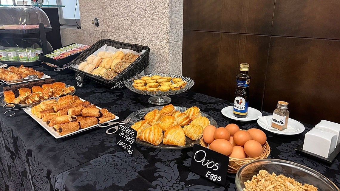 Breakfast buffet at Flag Hotel Barcelos: pastries, bread, eggs, and granola.
