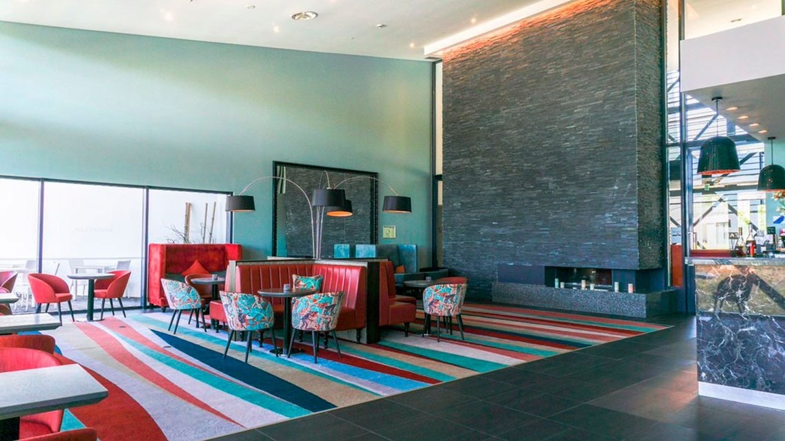Lounge moderno do Monchique Resort & SPA by Flagworld Hotels com lareira e tapete colorido.