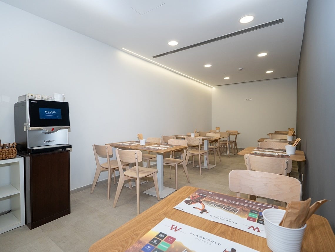 Modern dining area at Flag Hotel Lisbon Sintra with coffee machine and tables.