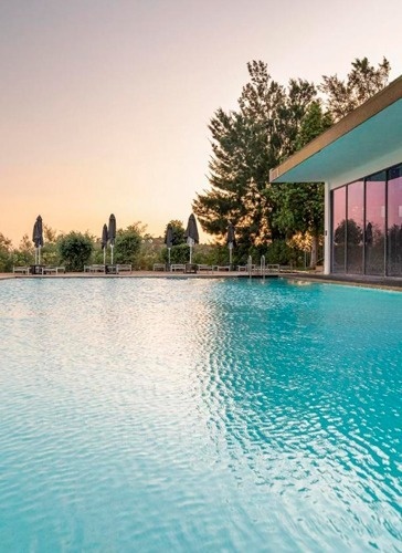 a large swimming pool with umbrellas and chairs around it