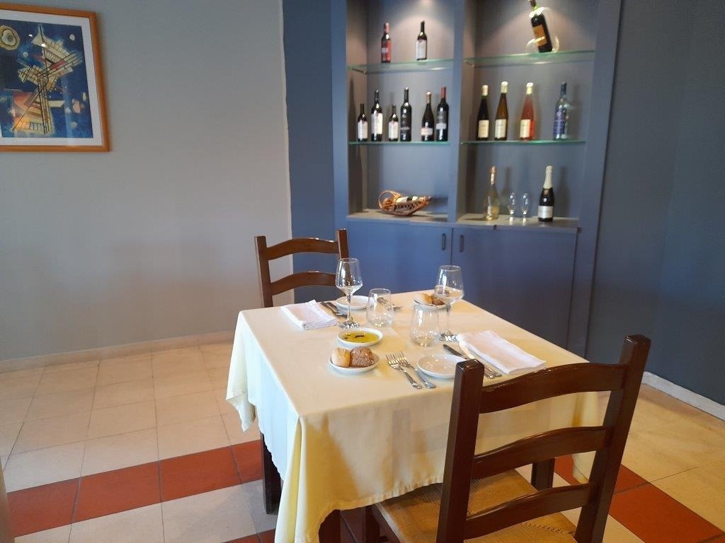 Set table for two at Flag Hotel Guimarães Fafe, featuring artwork and wine bottles.