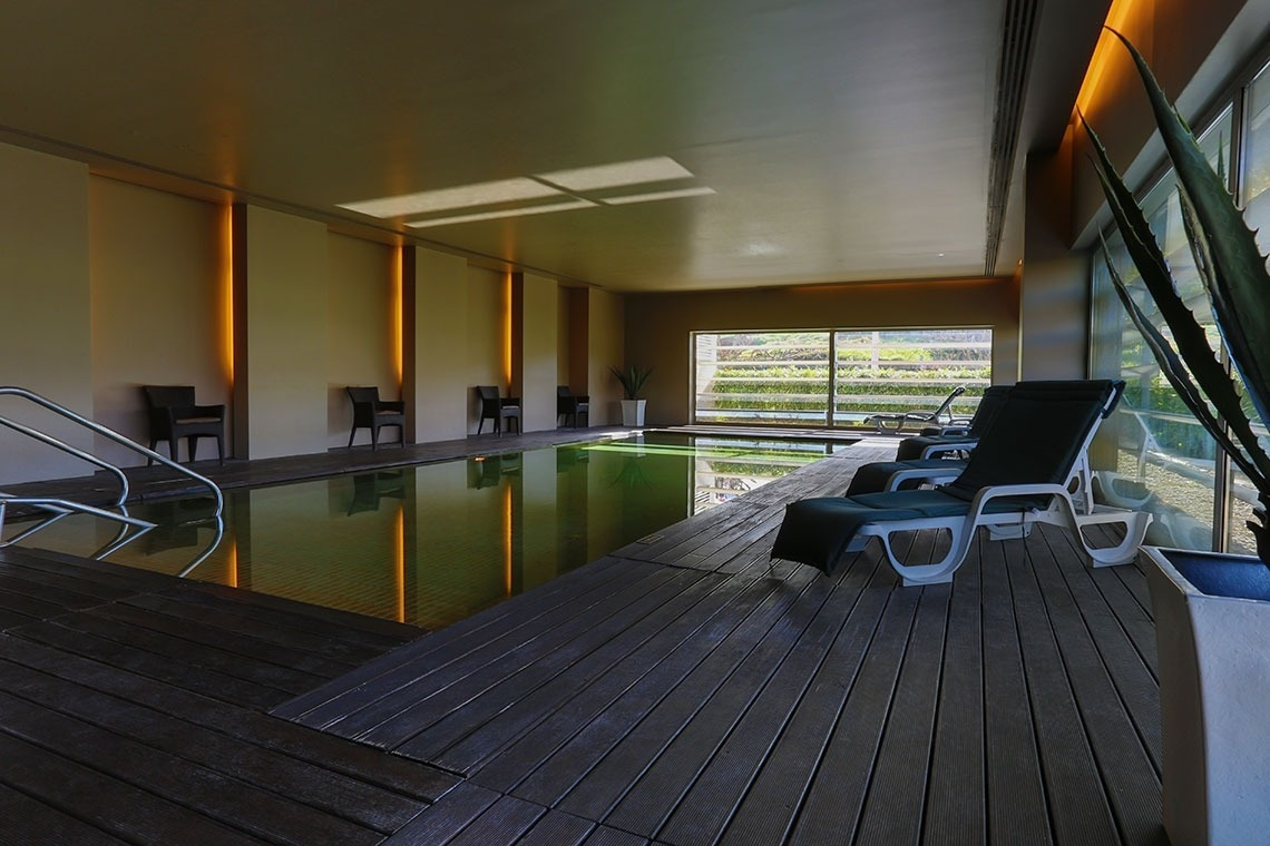 Indoor pool with loungers and views at Golden Tulip Sao Joao da Madeira | Official website