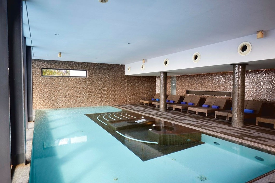 Piscina interior com espreguiçadeiras em Monchique Resort & SPA by Flagworld Hotels | Website oficial