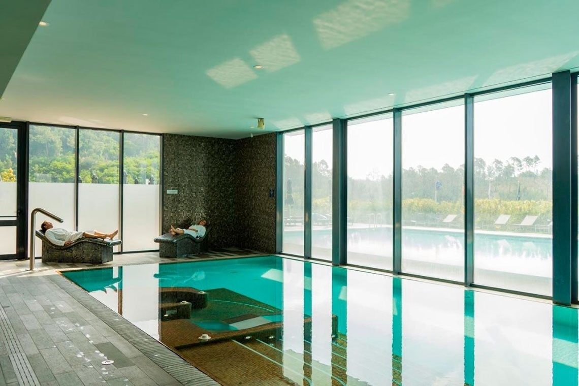 Piscina interior com vista para o exterior, relaxamento no Monchique Resort & SPA by Flagworld Hotels.