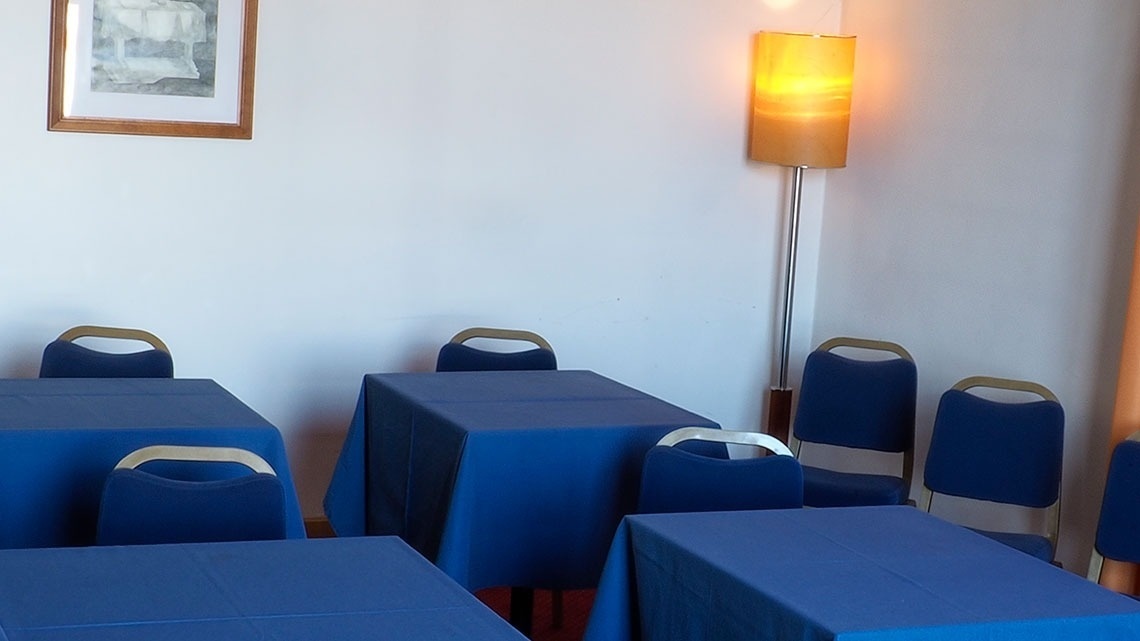 Salão de eventos do Flag Hotel Porto-Maia com mesas azuis e cadeiras, iluminação ambiente.