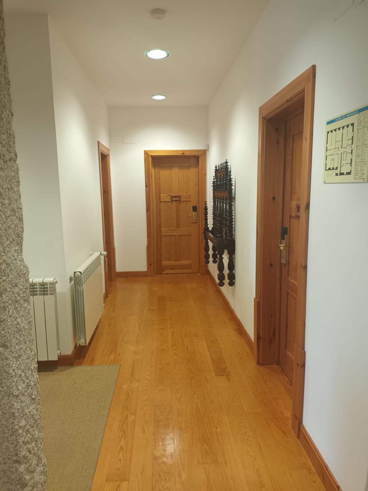 Corredor de hotel em madeira com portas, aquecedores e mapa de evacuação. Lam Hotel Convento do Desagravo