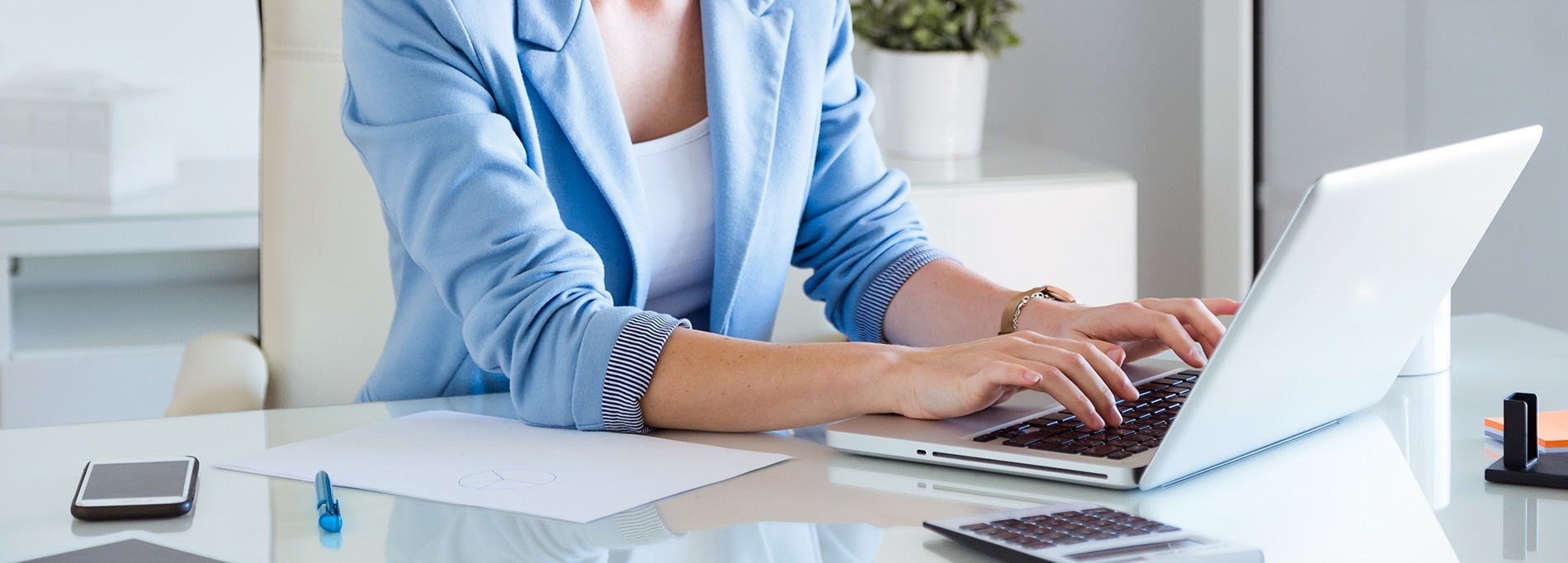 a woman in a blue jacket is typing on a laptop