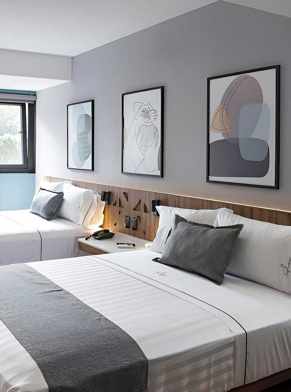 a hotel room with two beds and three paintings on the wall