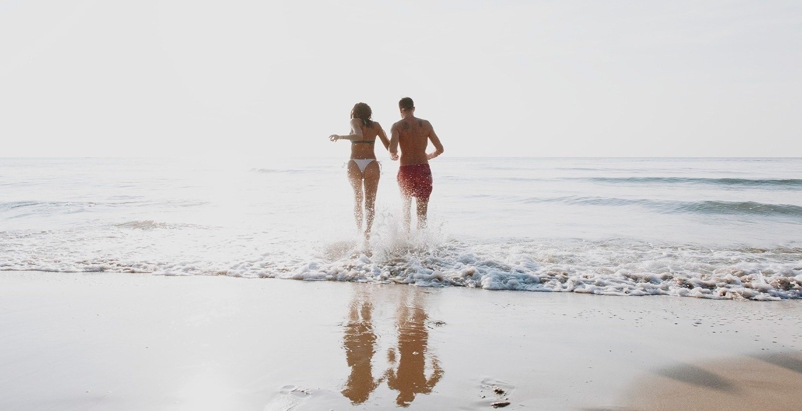 a man and a woman are standing in the ocean holding hands