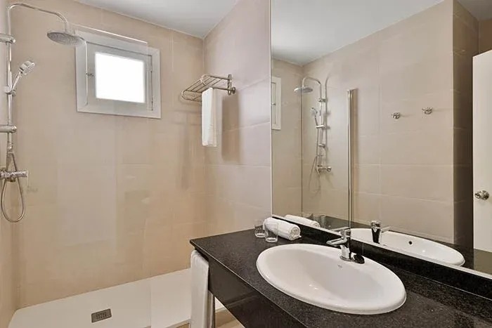 a bathroom with a sink , mirror and shower .