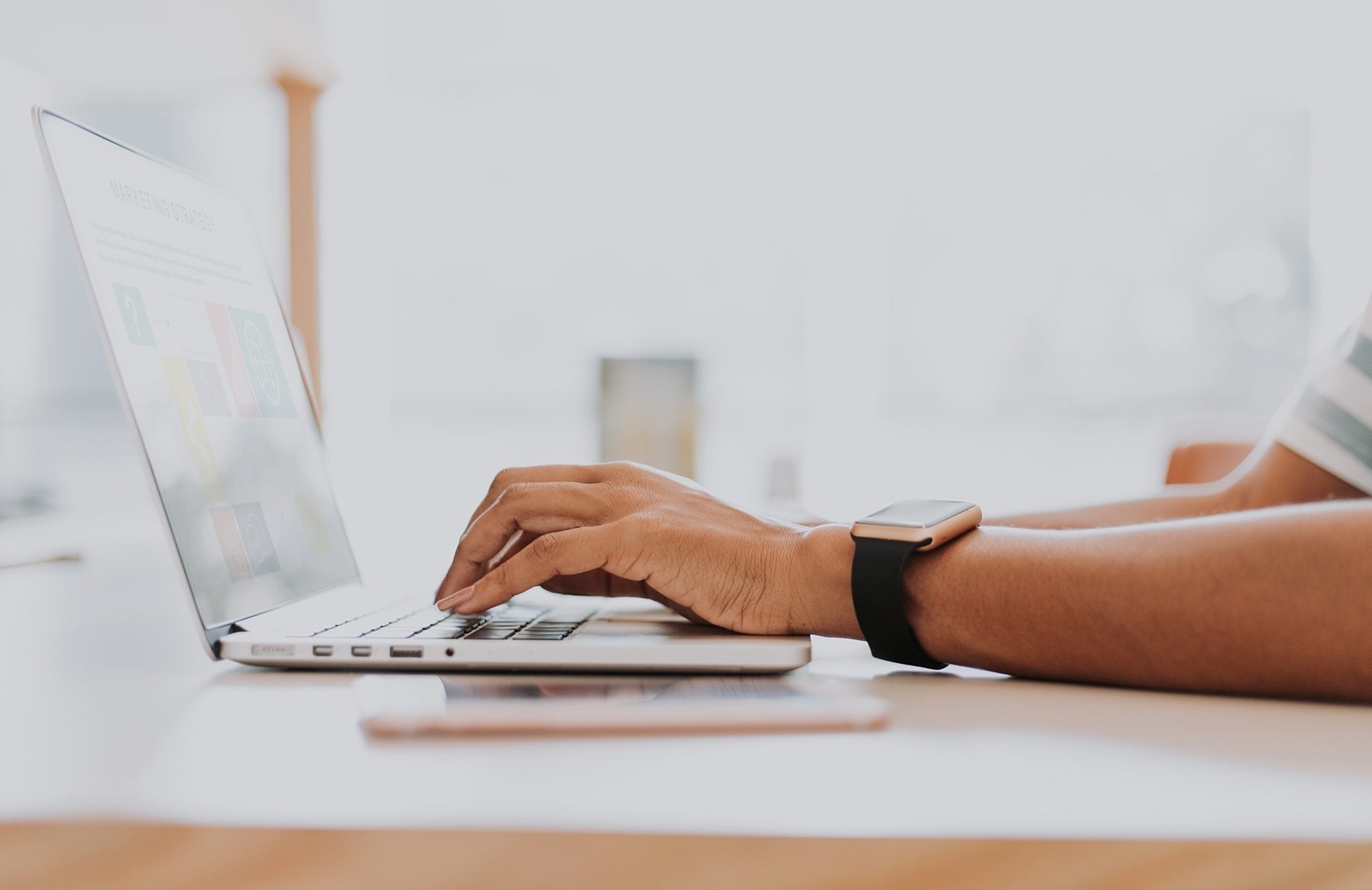 eine Person arbeitet an einem Laptop und trägt eine smart watch