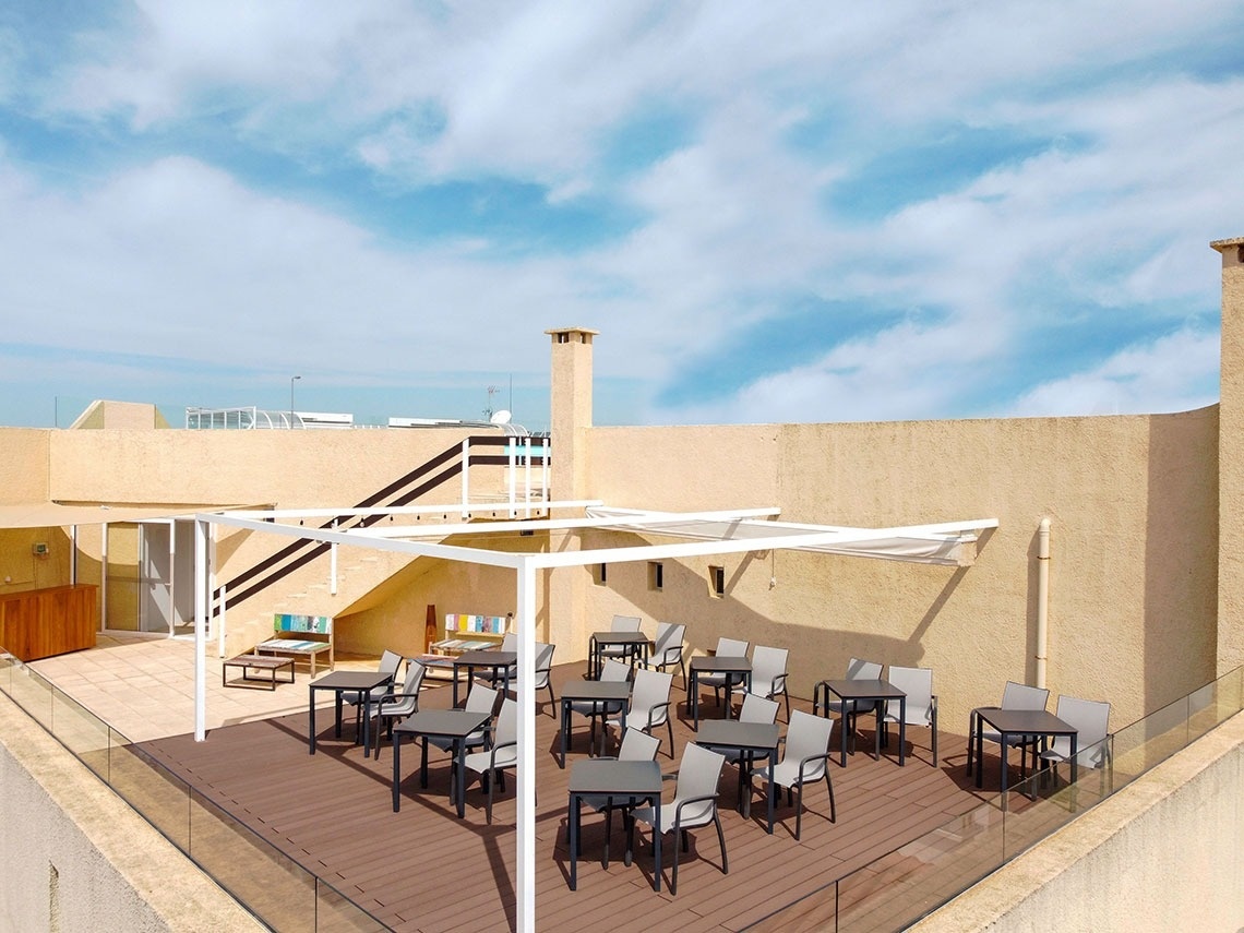 a patio with tables and chairs under a white pergola