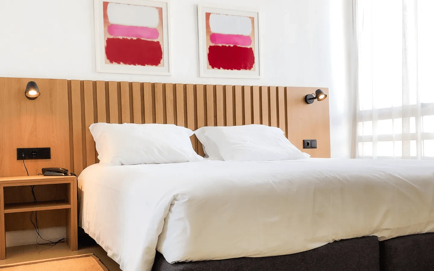 a hotel room with a bed and two paintings on the wall