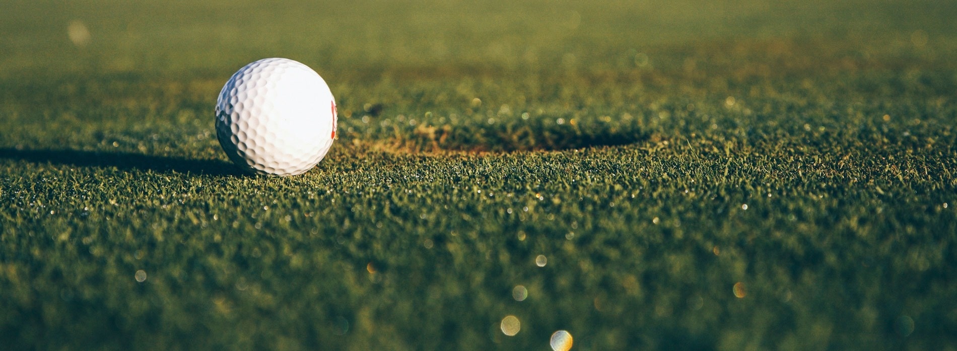 een golfbal zit op een groene golfbaan naast een gat