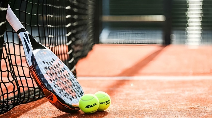 uma raquete de tênis e duas bolas de tênis na quadra