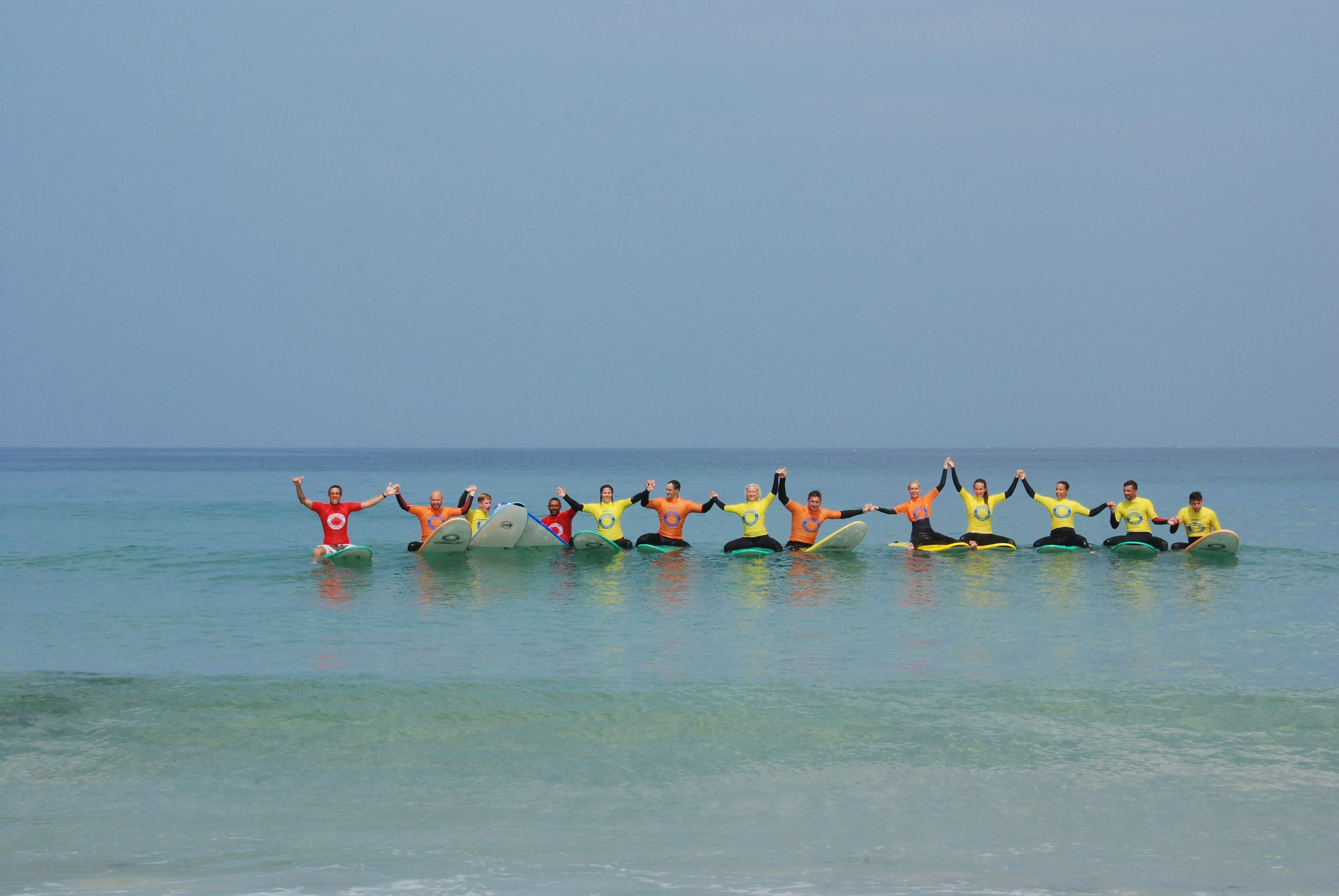 Grupo de surfistas en FreesurfCamp unidos de las manos en el mar.