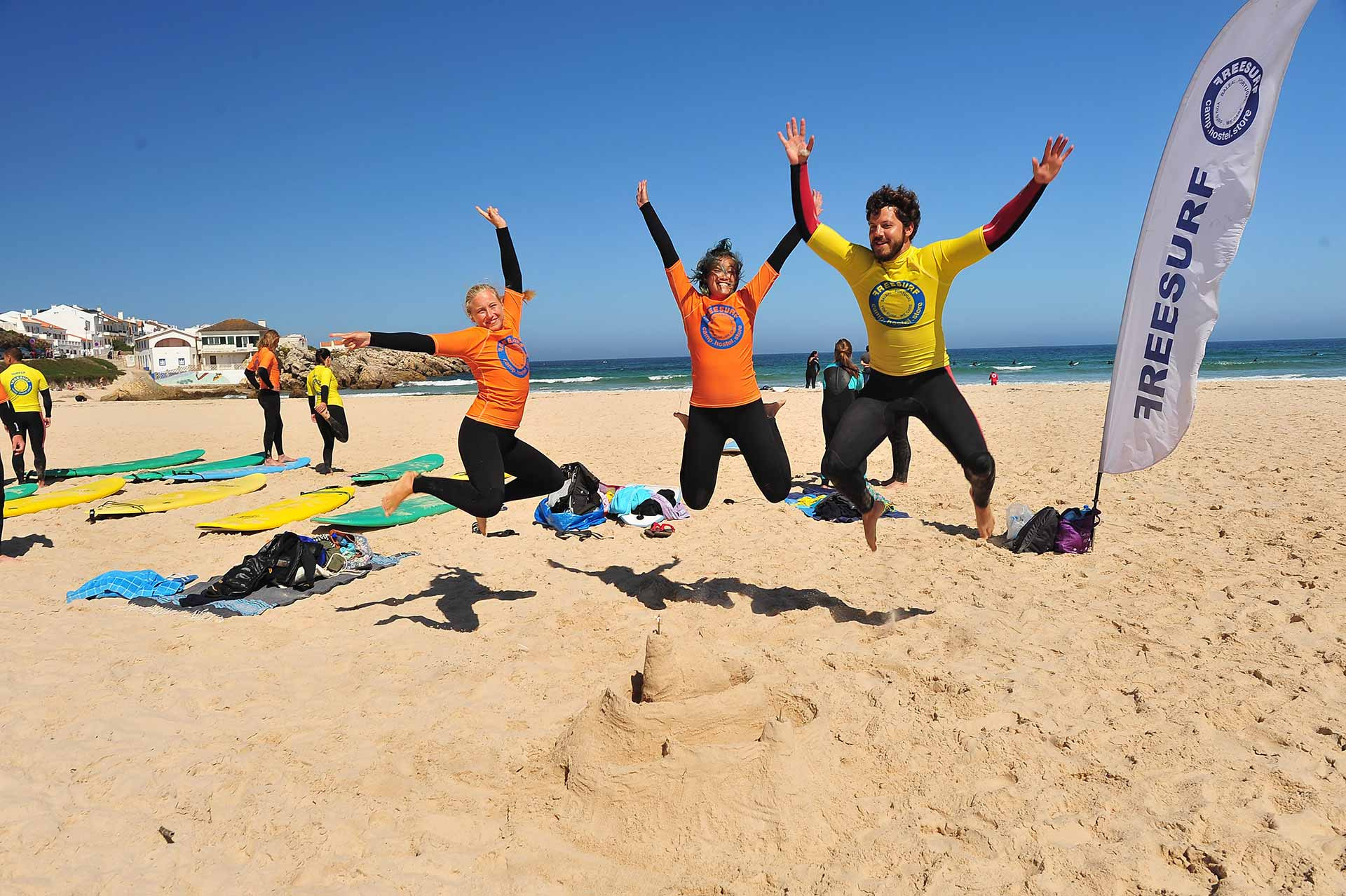 Jóvenes alegres saltando en la playa frente a FreesurfCamp.