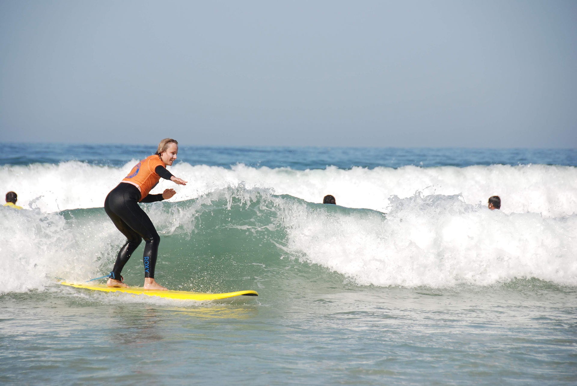 Mujer en tabla de surf, experiencia FreesurfCamp ideal en la playa.