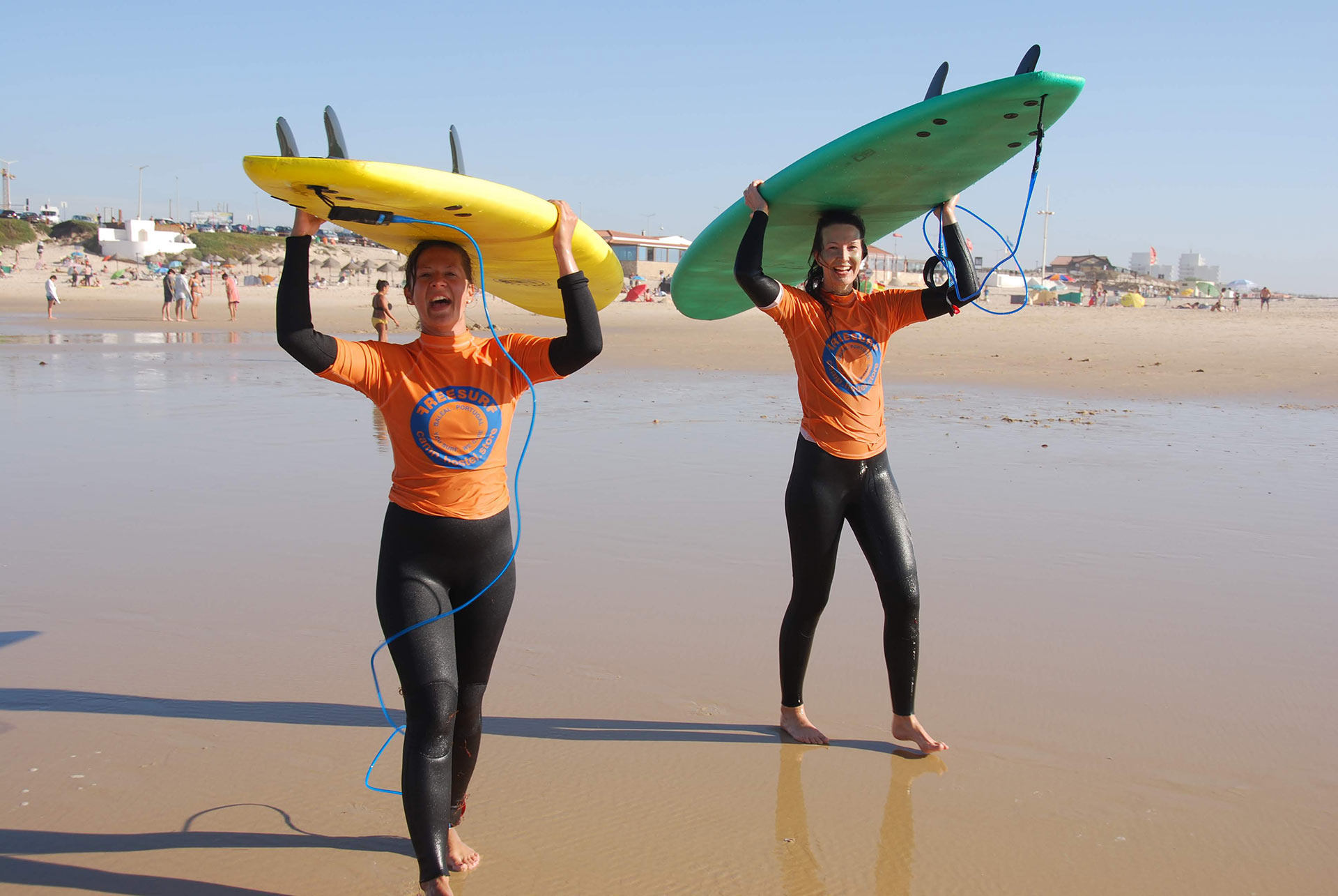 Dos surfistas sonrientes en la playa llevando tablas de surf, ideal para FreesurfCamp.