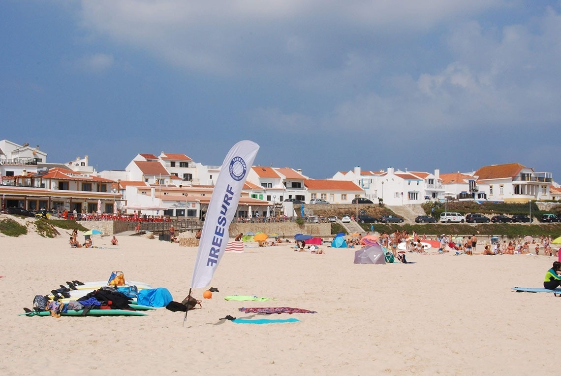 Uma praia movimentada com banhistas, guarda-sóis e uma bandeira 