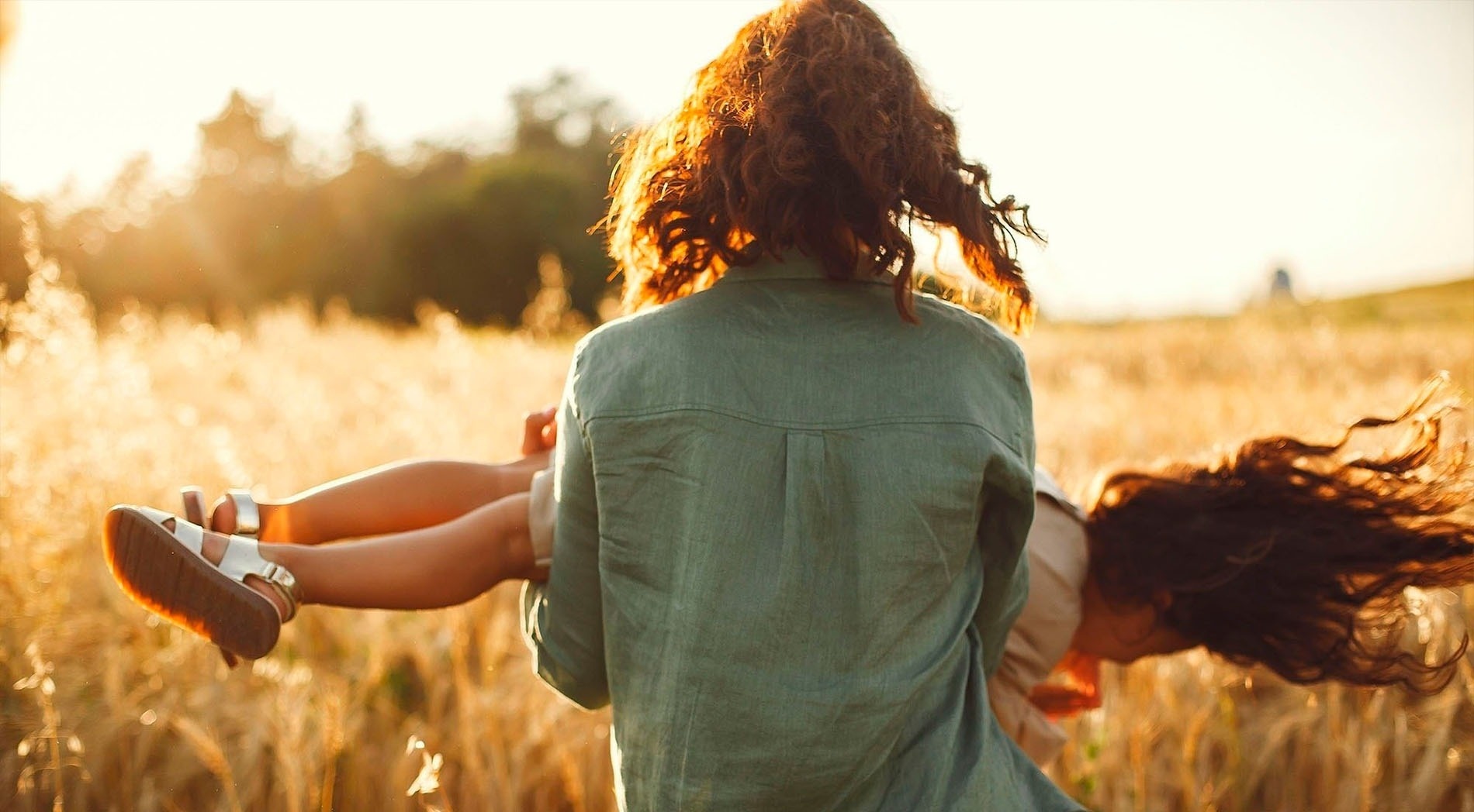 una mujer sostiene a una niña en sus brazos en un campo de trigo