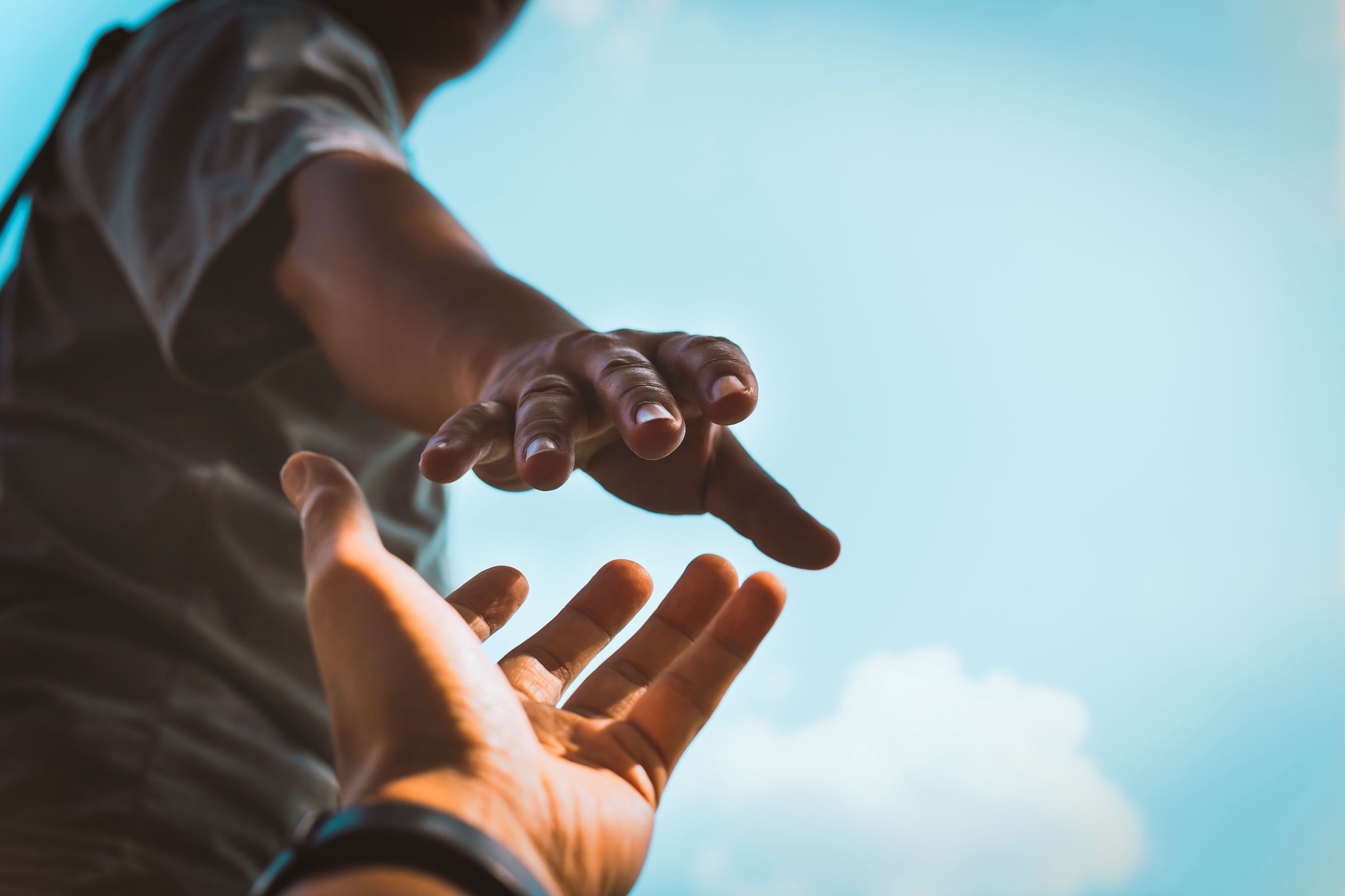 una persona sostiene la mano de otra persona contra un cielo azul