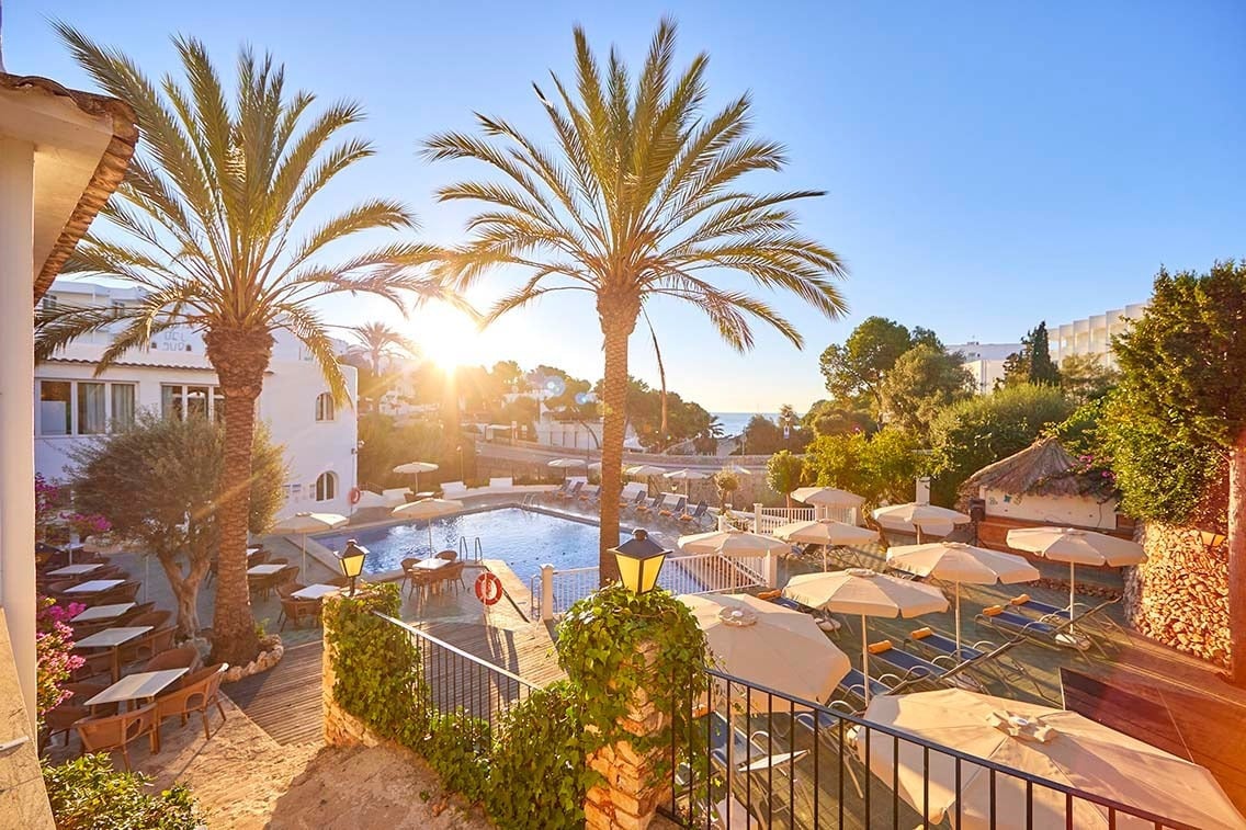 Hotel Gavimar Cala Gran Costa del Sur: piscina y palmeras al atardecer.