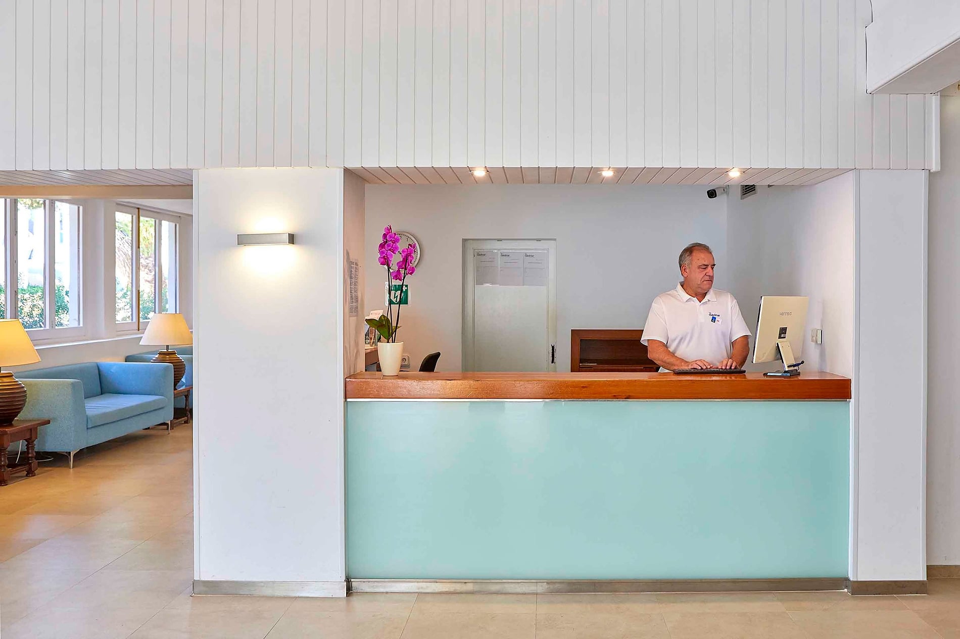 Recepción del hotel Gavimar Cala Gran Costa del Sur, Cala d'Or. Recepcionista en el mostrador.