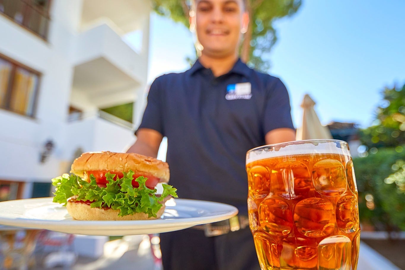 Waiter with burger and beer at Gavimar Cala Gran Costa del Sur | Gavimar Hotels | Cala d'Or.